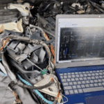 Technician using laptop with Mercedes wiring diagram to diagnose SAM, ECU, and CAN Bus faults in engine bay