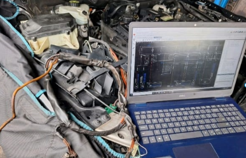 Technician using laptop with Mercedes wiring diagram to diagnose SAM, ECU, and CAN Bus faults in engine bay